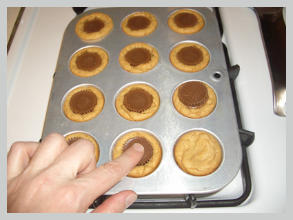 pushing peanut butter cup into top of baked peanut butter cookie