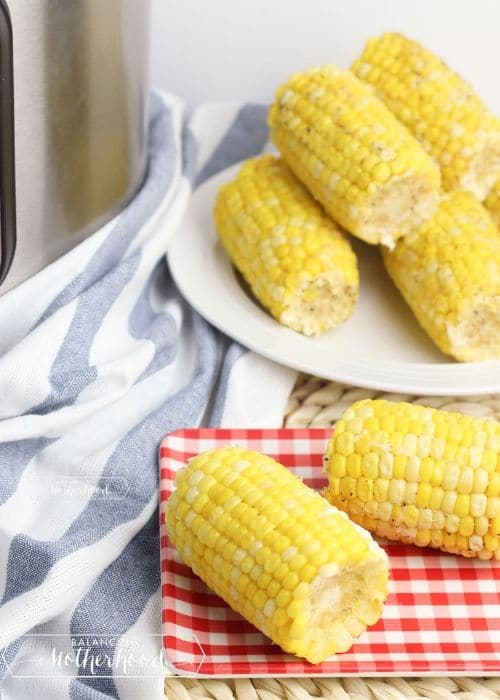 corn on cob on plate, and red checkered napkin