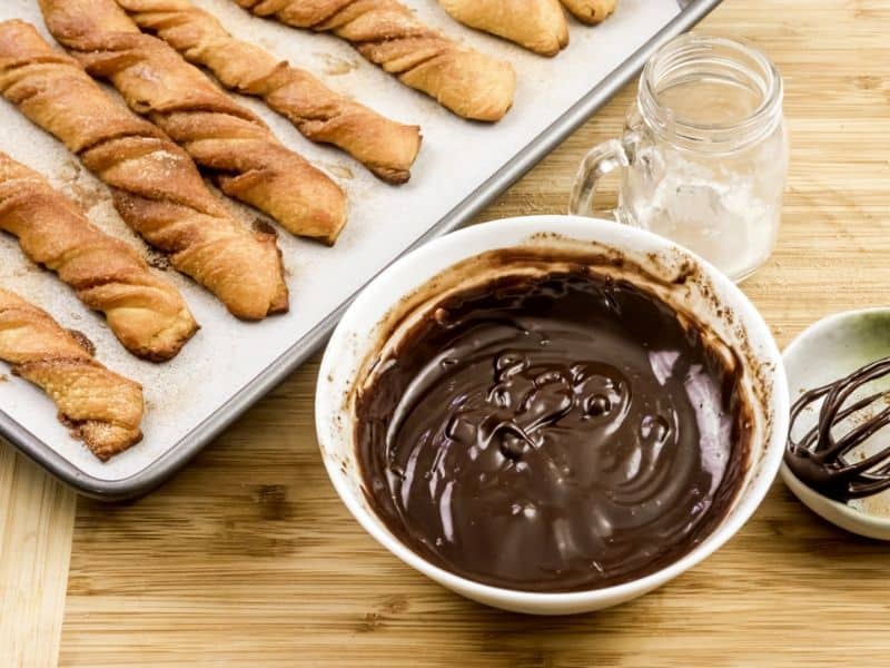 chocolate sauce in bowl next to baked churros