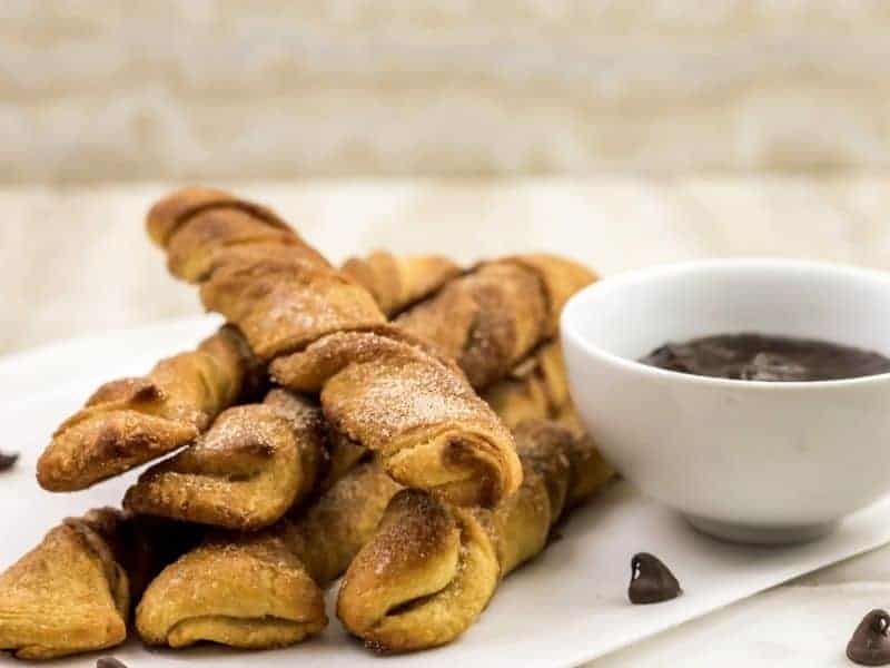 baked churros on table with chocolate dipping cause