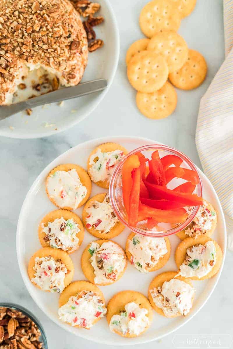 Pineapple cheeseball served on crackers with slices of red peppers