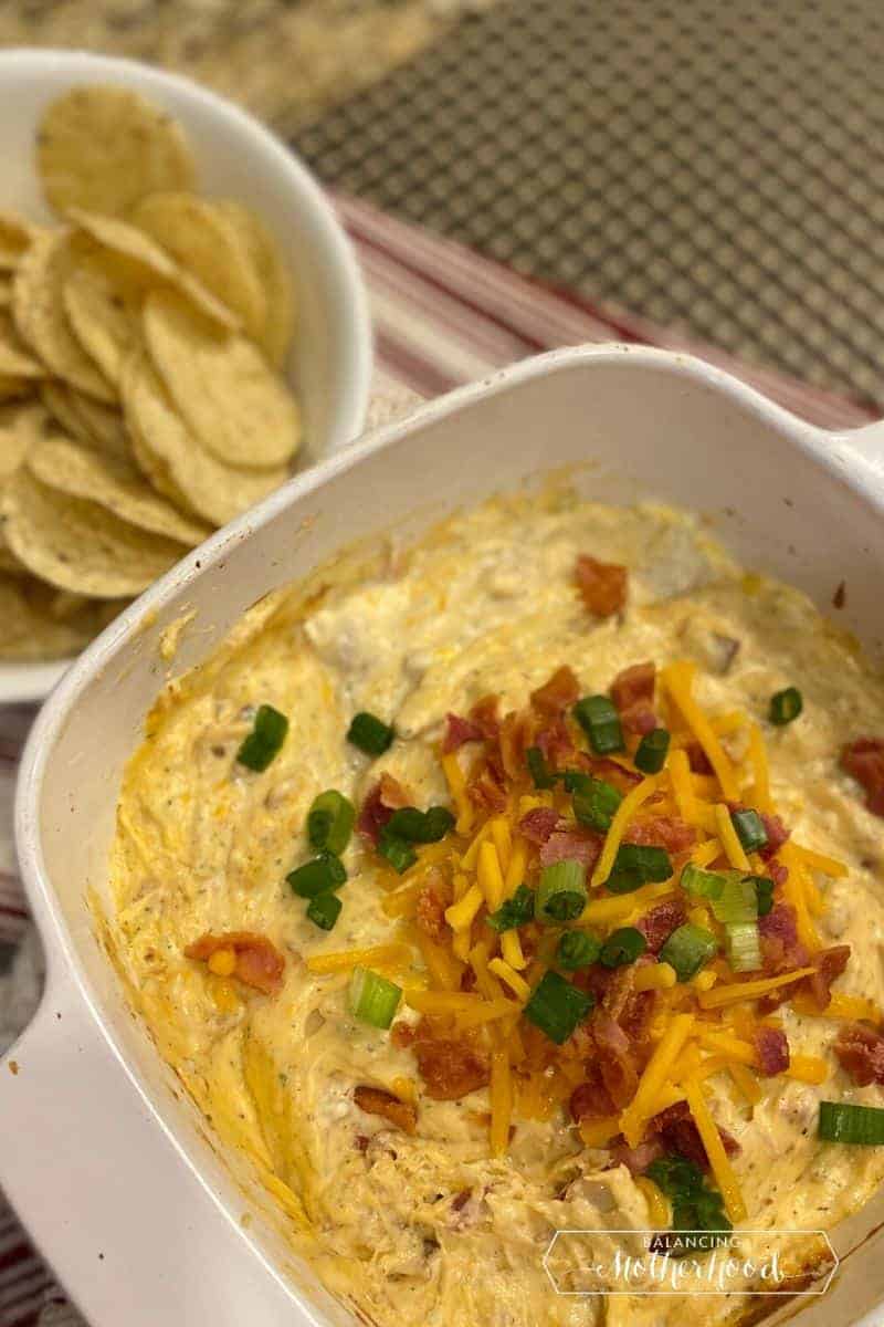 cheddar cheese dip with bacon and scallions next to tortilla chips