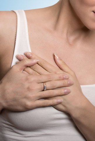 woman clutching breast in pain while wearing a tank top
