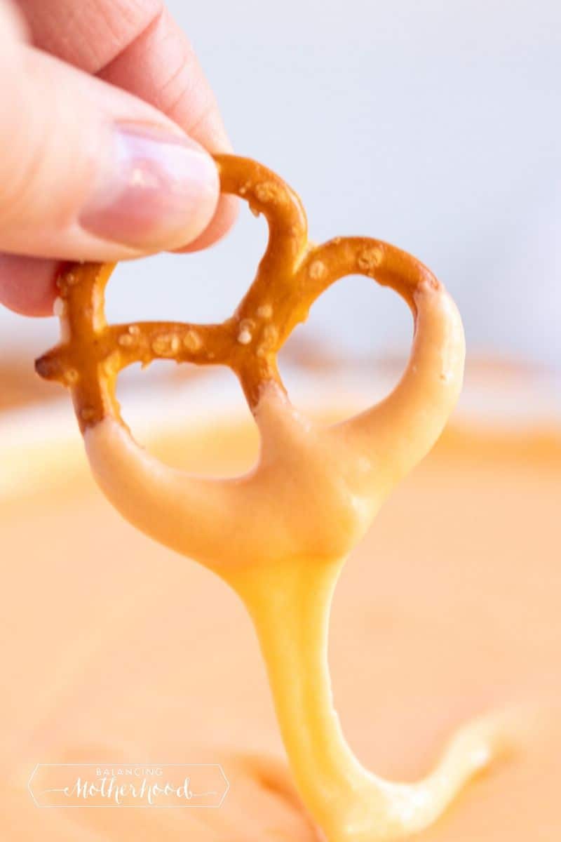 pretzel being dipped into beer cheese dip