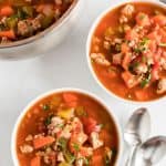 two bowls of minestrone soup with spoons