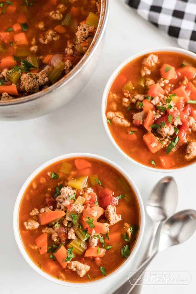 two bowls of minestrone soup with spoons