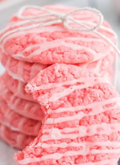 A stack of pink sugar cookies with strawberry icing on top.
