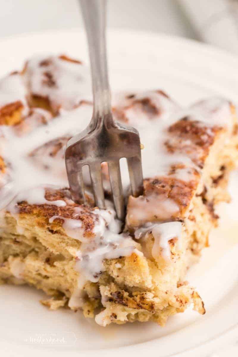 fork taking a bite out of cinnamon roll french toast slice