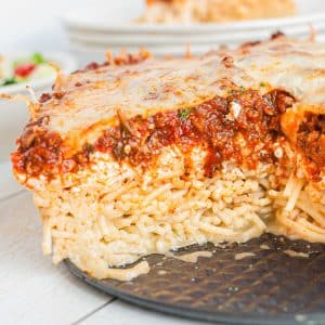 A slice of spaghetti and meatballs pie on a plate.