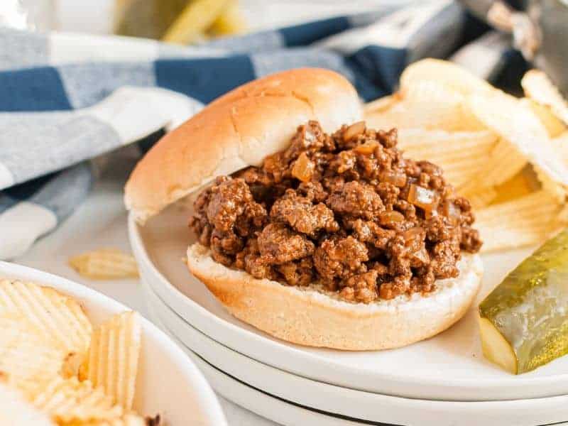 sloppy joe on bun with chips and a pickle