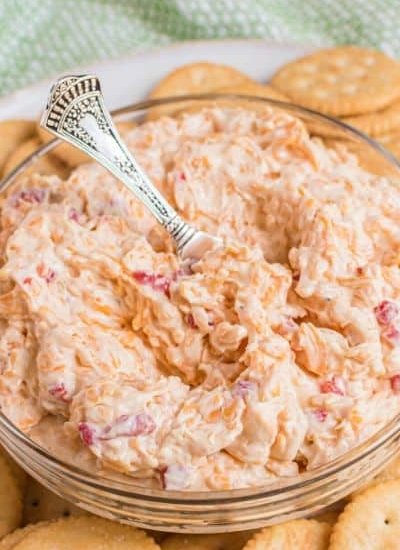 A bowl of the best cheesy dip with crackers and a spoon.