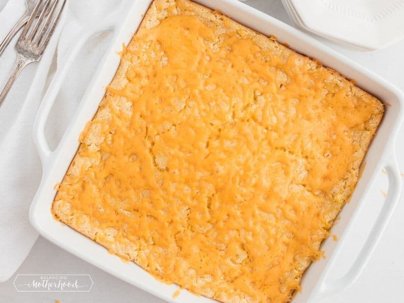 square casserole dish with cooked corn casserole with melted cheese on top