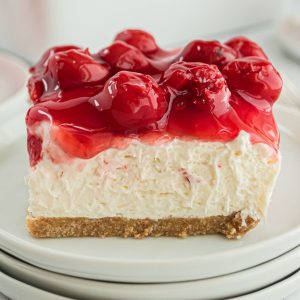 square cheesecake slice with cherry pie filling on top