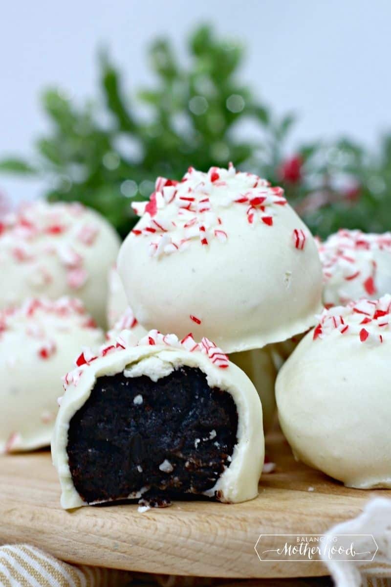 Oreo truffles with crushed candy canes on top, stacked with a bite out of one. 