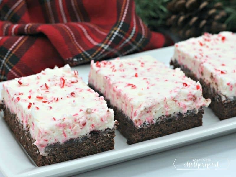 three brownies with candy cane buttercream frosting on a plate