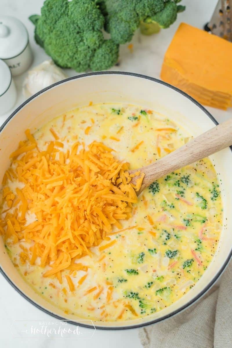 pot of broccoli cheese soup with fresh shredded cheddar cheese just put in