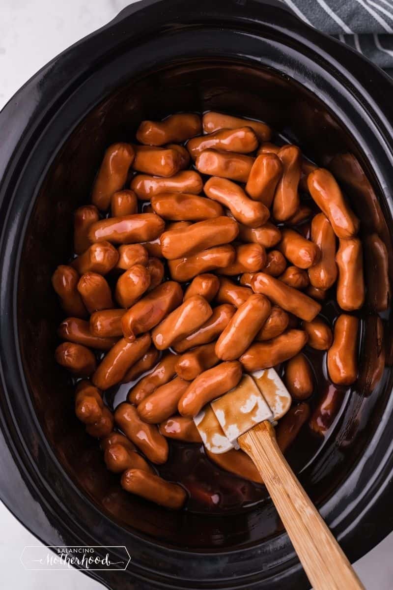 crockpot with smokies and a wooden spoon