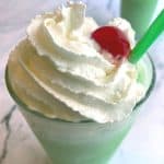 top of a green milkshake with whipped cream and a cherry