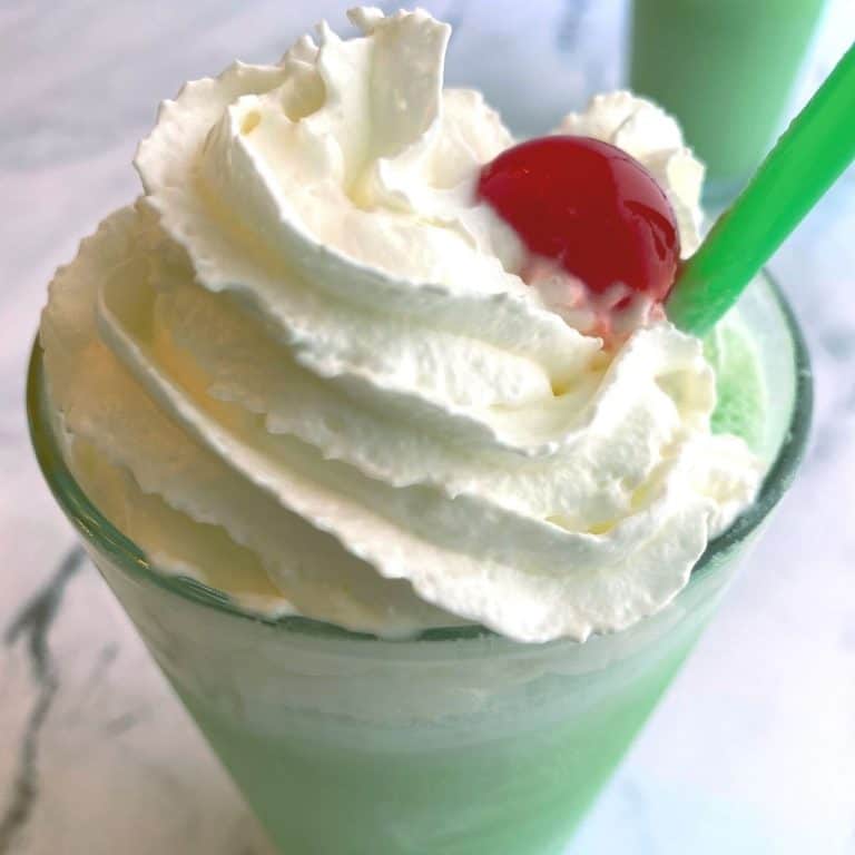 top of a green milkshake with whipped cream and a cherry