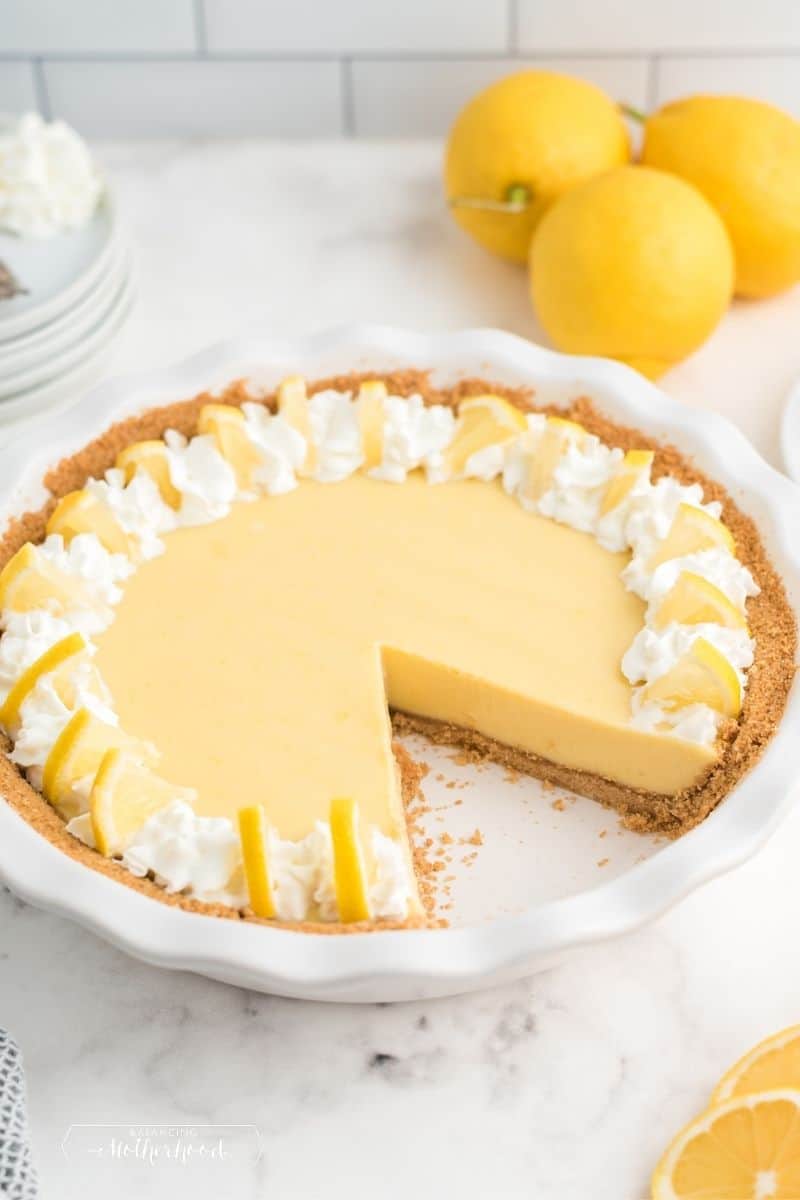 lemon pie with slice cut out with lemons in background