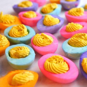 pink, orange, blue, and purple egg whites with deviled egg mixture pipped in middle