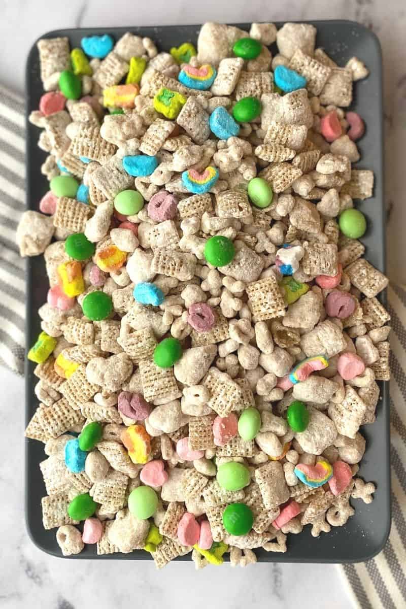 plate topped with a heaping pile of Lucky Charms muddy buddies with green m&ms and Lucky Charms marshmallows