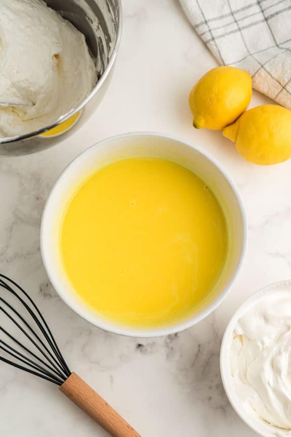 A bowl of Lemon Lush next to a bowl of whipped cream.