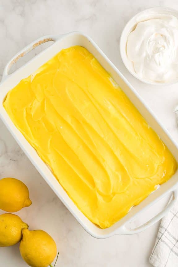 A Lemon Lush dessert presented in a white baking dish, topped with whipped cream.