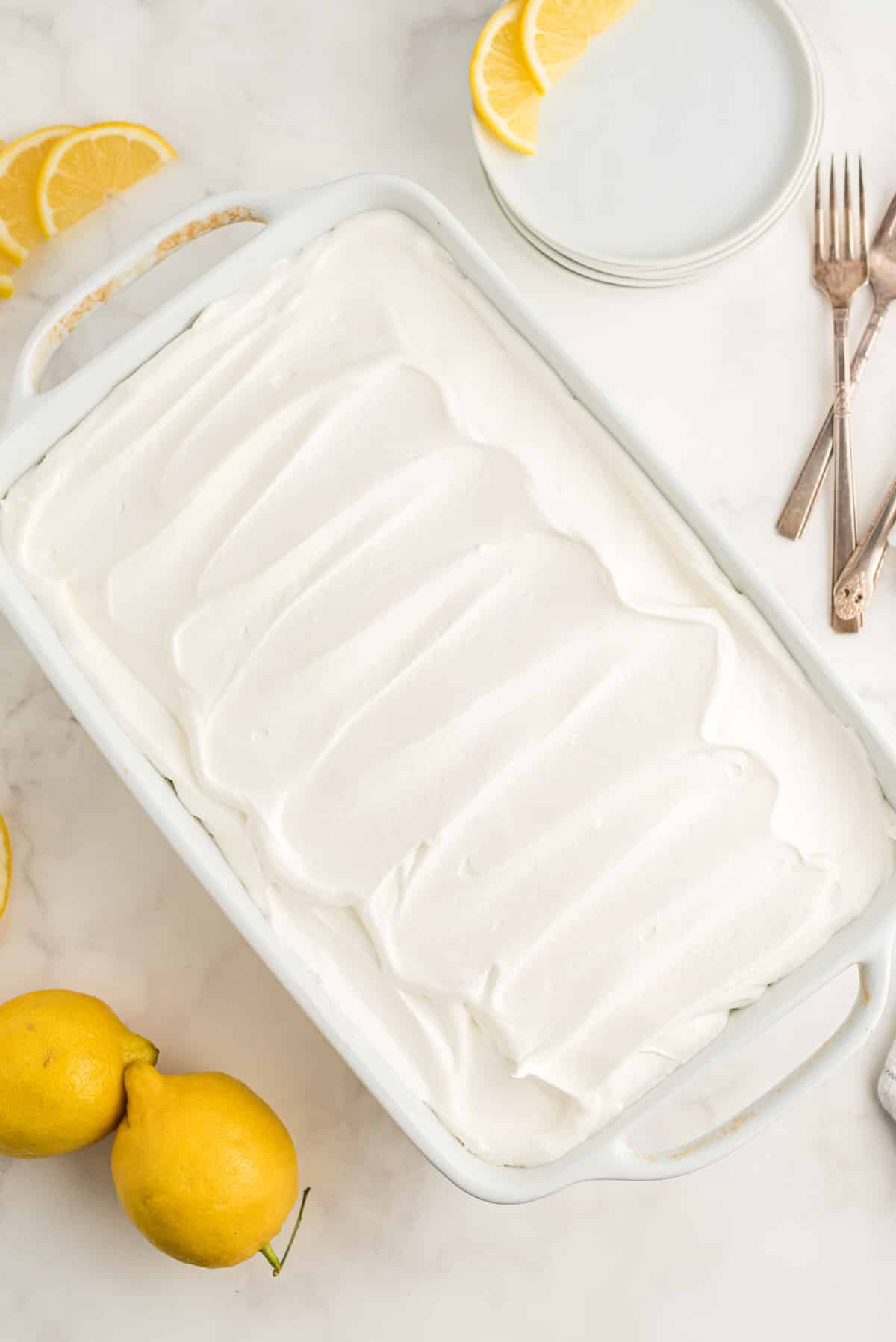 A Lemon Lush dessert in a white baking dish, topped with whipped cream.