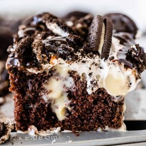close up of a slice of chocolate cake with vanilla pudding and oreos on top