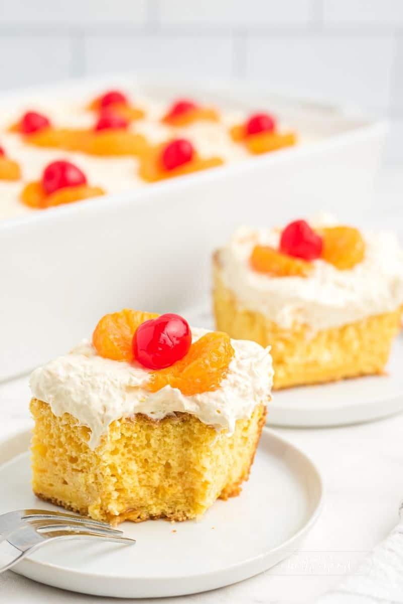 two slices of cake with mandarin oranges and a cherry on top