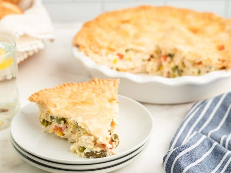 slice of chicken pot pie on plate with whole pie in background