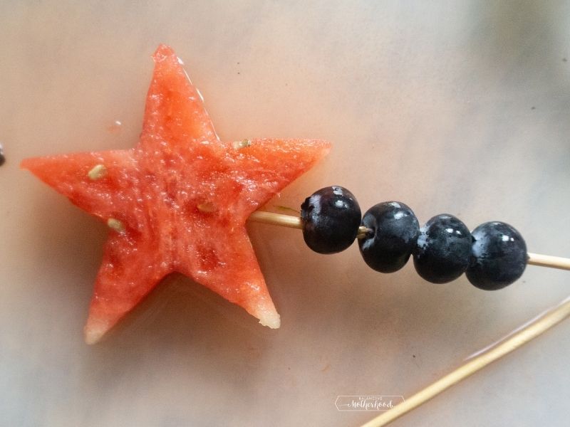 watermelon star on top of a skewer with some blueberries on bottom of skewer