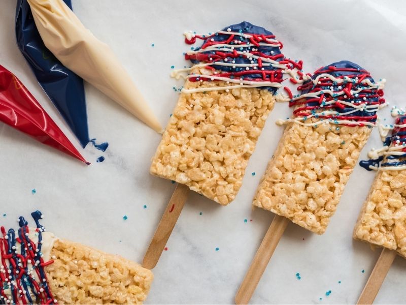 rice krispy treats with popsicle sticks in them, red, white, and blue piping bags
