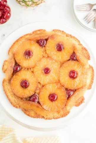 round cake on white plate. Golden pineapple rings with a cherry in the middle of each one