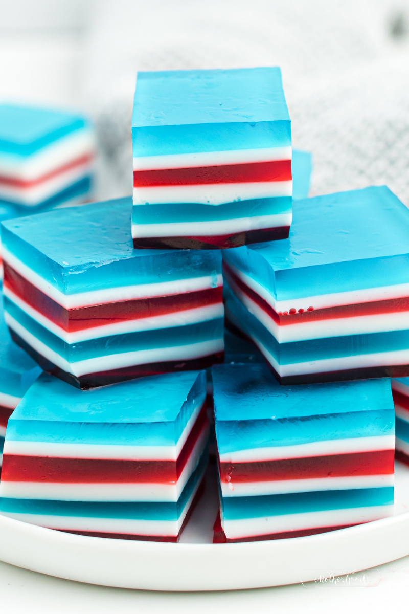 red, white and light blue layers of jello squares stacked on plate