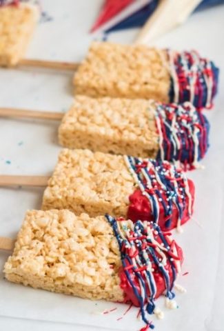 rice krispy pops with popsicle sticks and decorated with red, white and blue chocolate on the tops