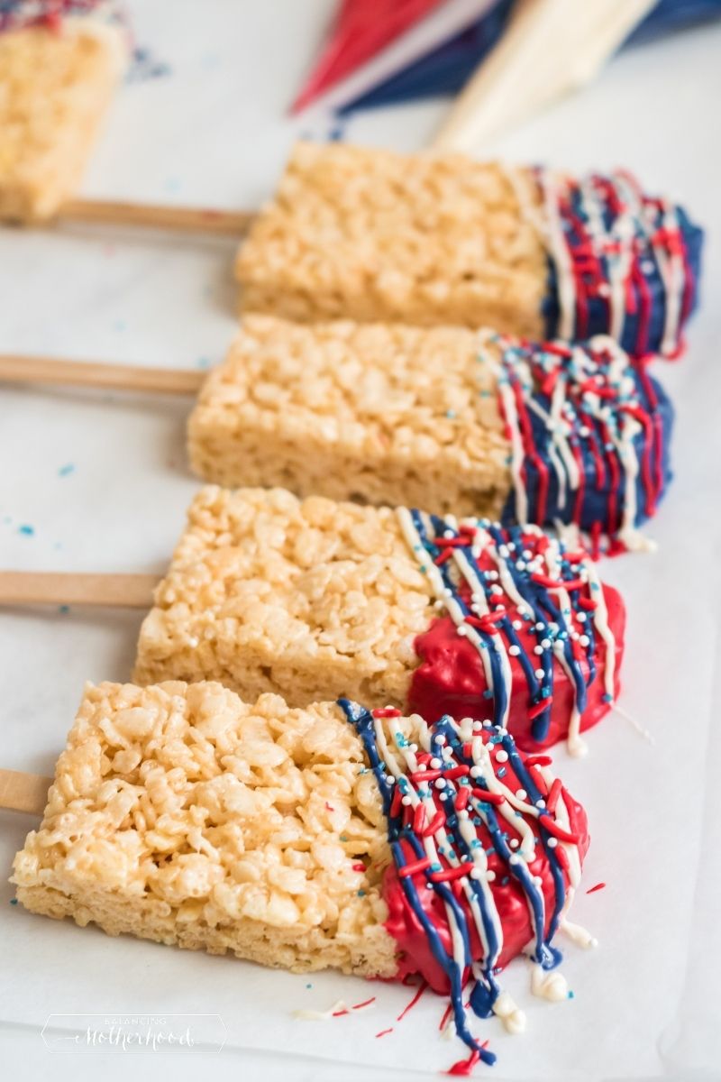 krispie treat pops on popsicle sticks with red, white, and blue chocolate drizzled on the top