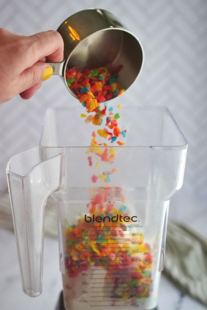 blender with cup pouring fruity pebbles cereal into milkshake