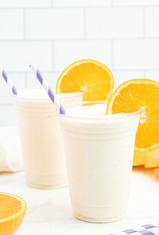 two cups with white milkshake and orange slices