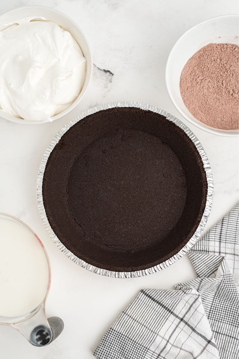 ingredients on white counter: Oreo pie crust, milk, Cool Whip, and powdered chocolate pudding mix