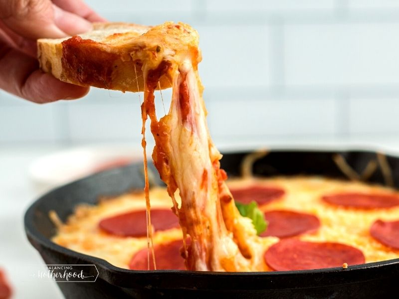 cheese being pulled from pan of pizza dip