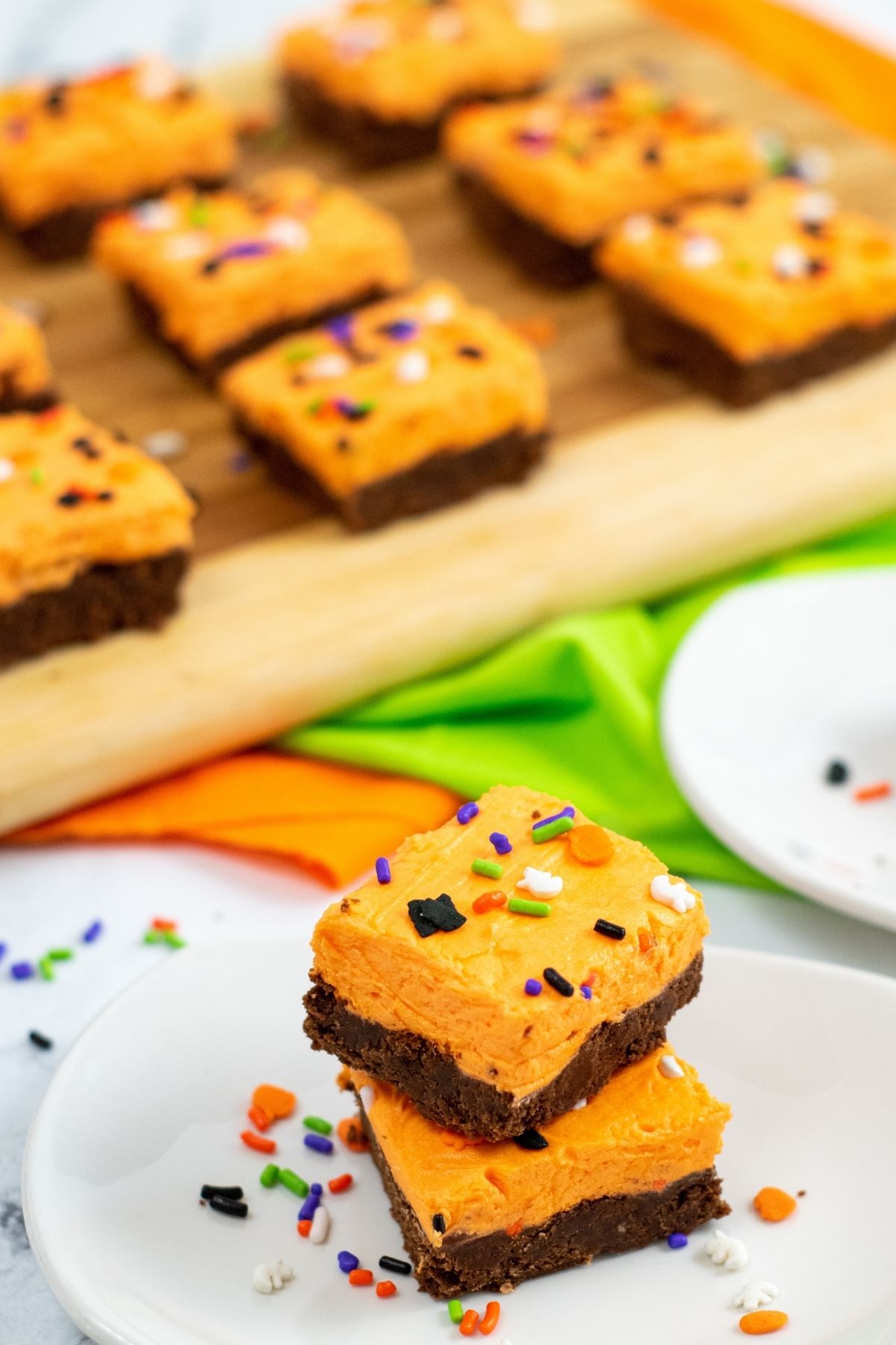 chocolate squares with orange frosting and Halloween sprinkles on cutting board