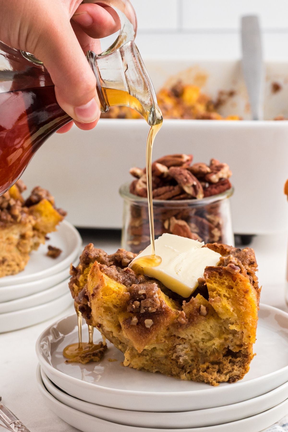 maple syrup being poured on a slice of pumpkin french toast casserole