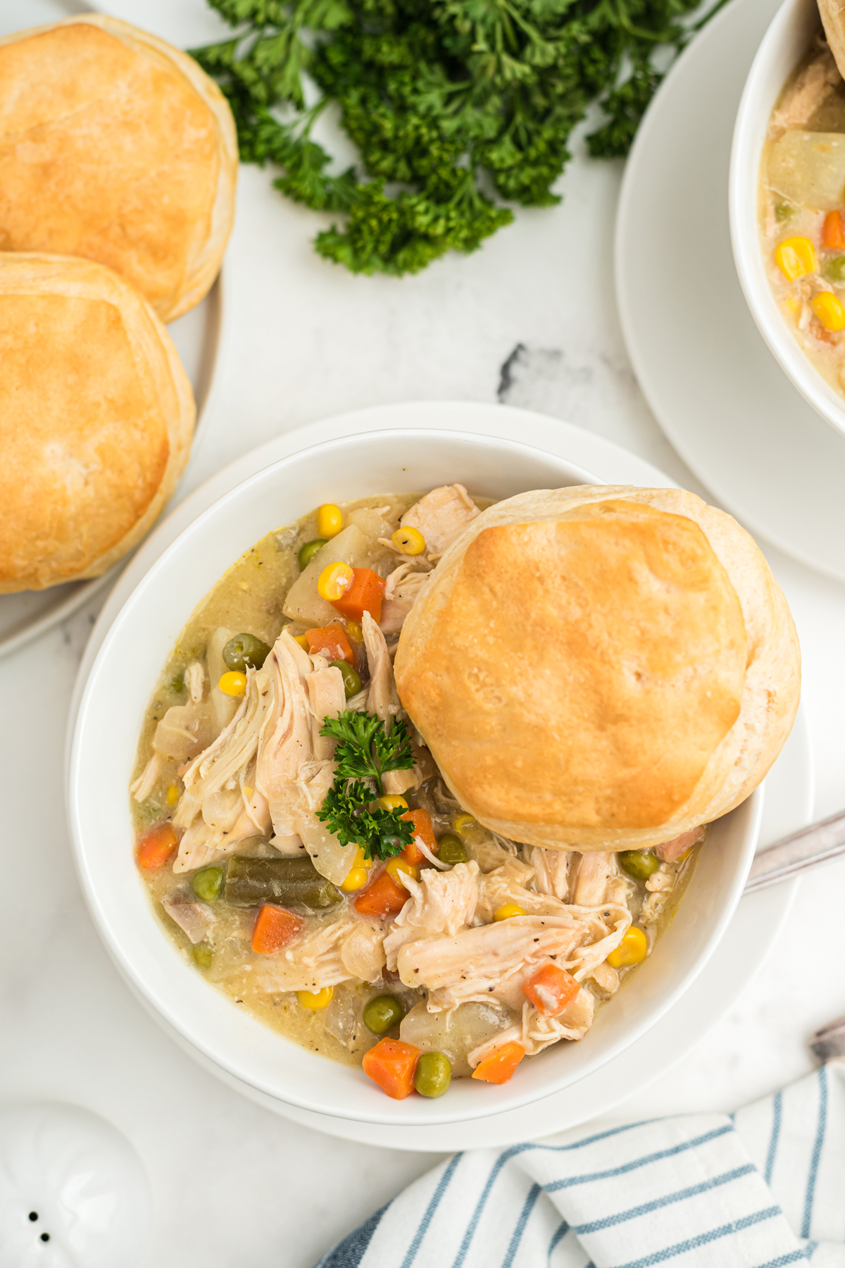 The slow cooker chicken pot pie on a white bowl with biscuits