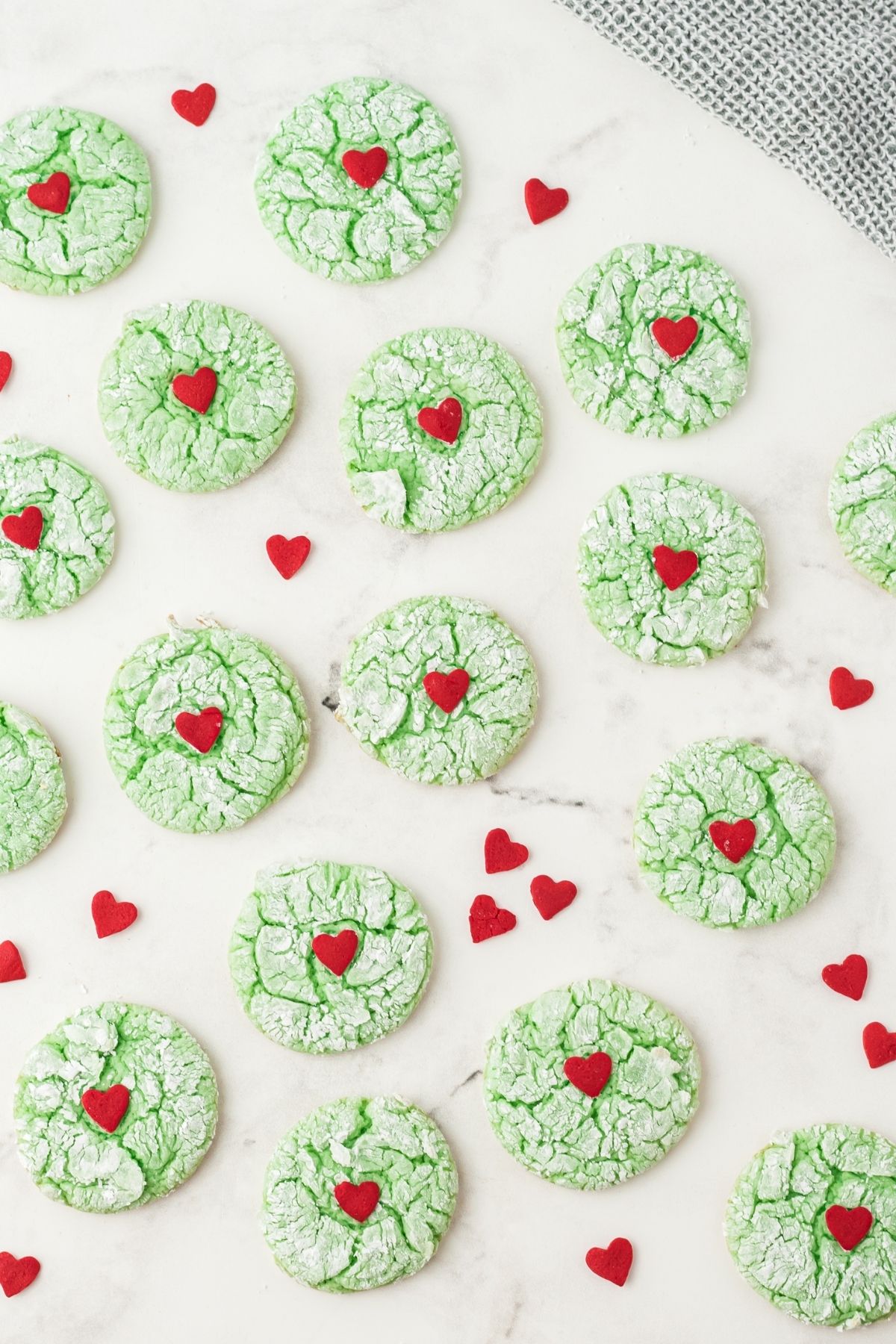 baked green cookies with cracks and a big red heart on white counter