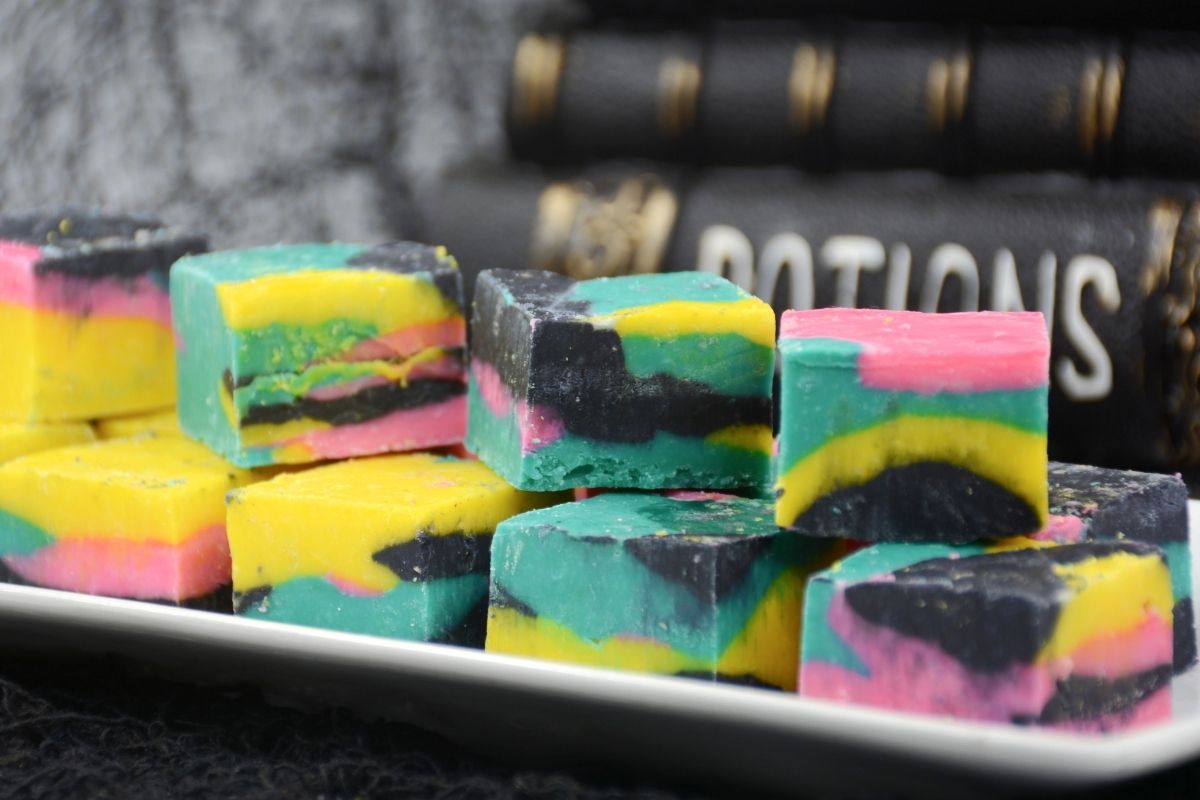 colorful fudge squares on white plate with potion books in background
