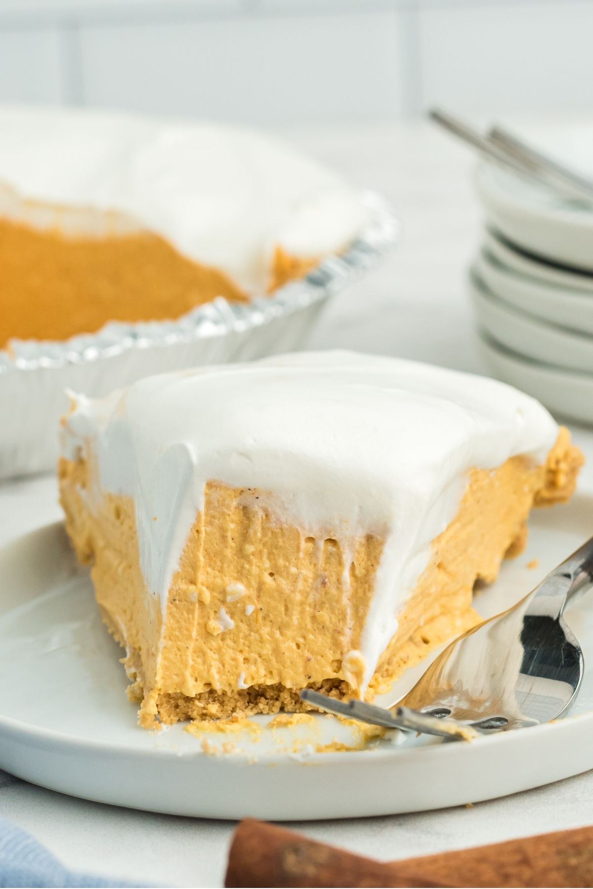 slice of no bake pumpkin pie with a bite out and cool whip on top