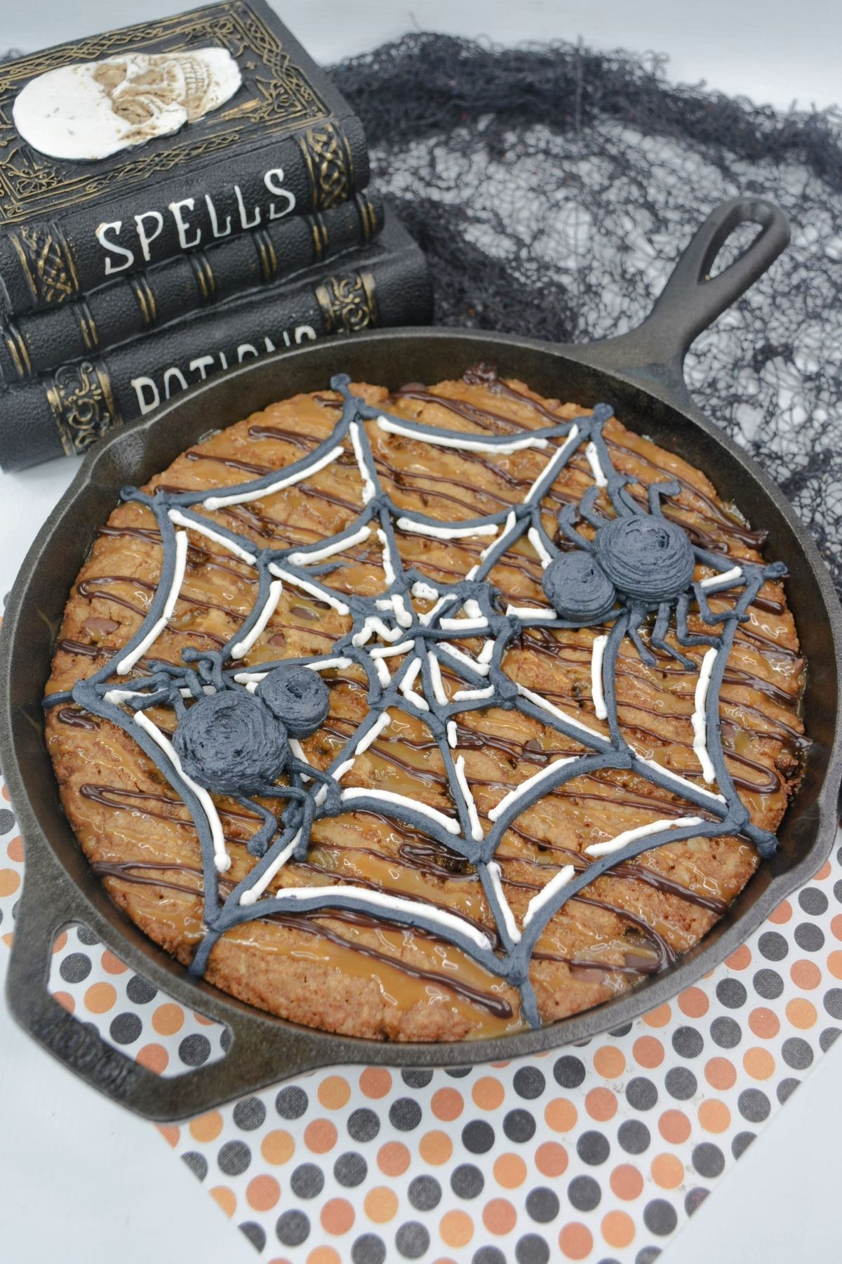 cast iron skillet with chocolate chip cookie and spider web design on top