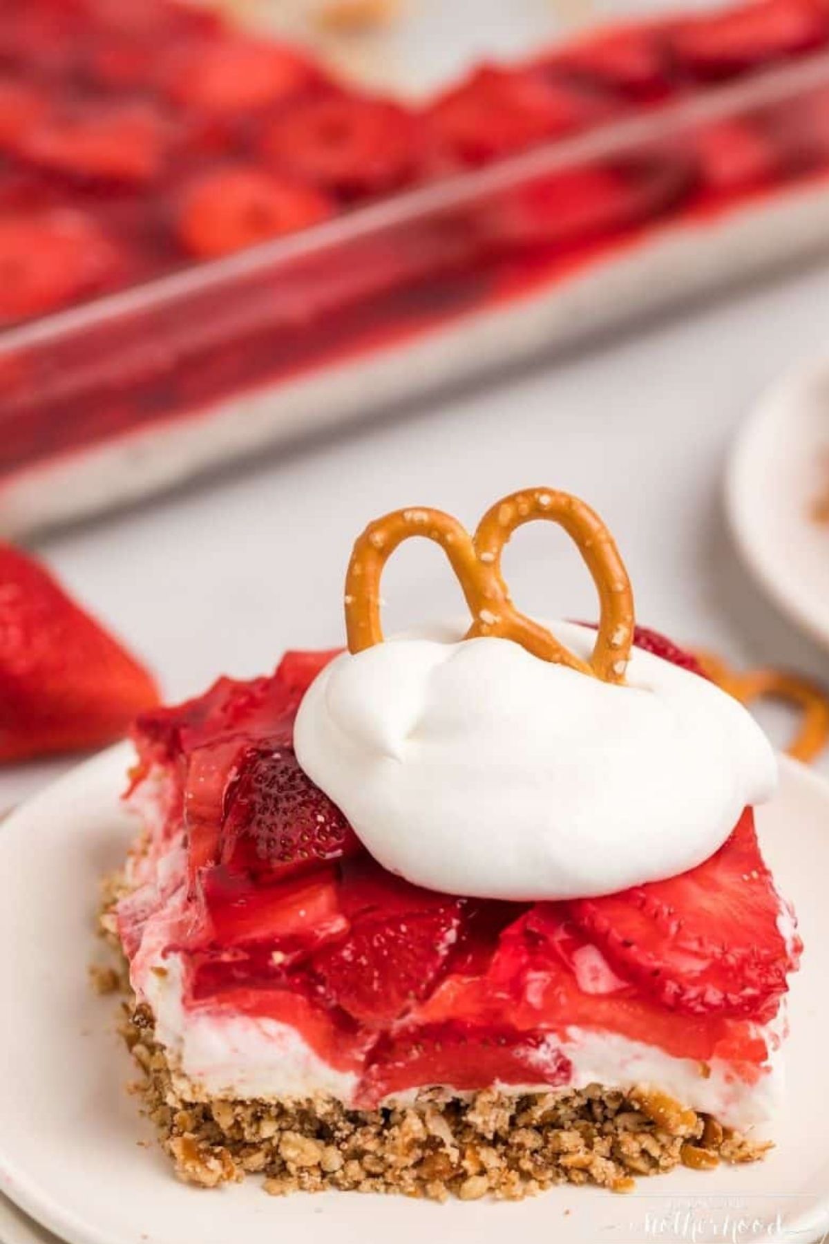 slice of strawberry pretzel salad with whipped cream and a pretzel on top